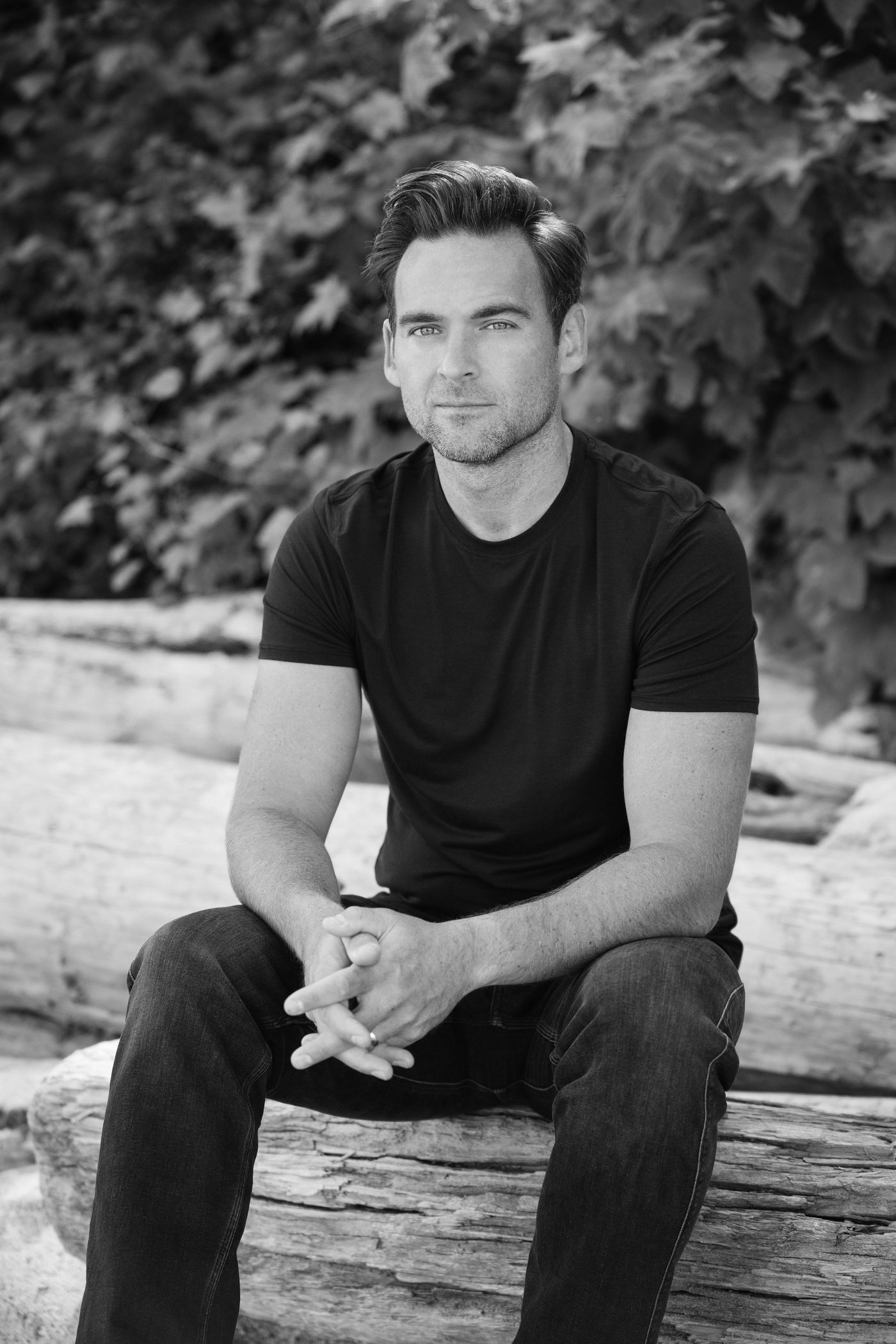 Joshua Matettore, seated, hands clasped, looking to camera.